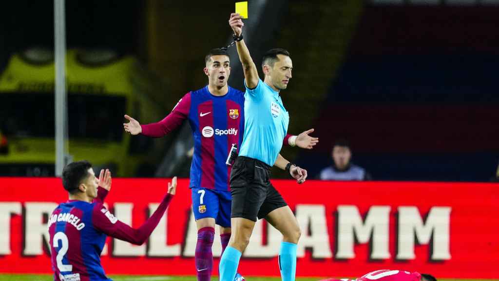 Sánchez Martínez, mostrando una cartulina amarilla a Cancelo durante el Barça-Atlético