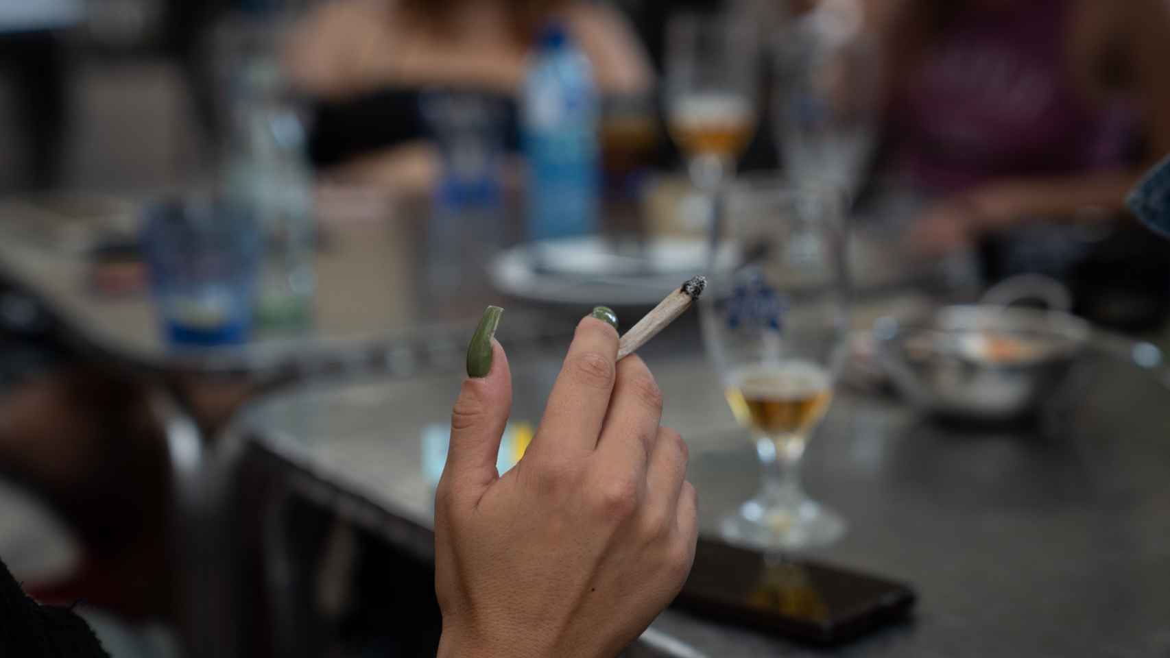 Una mujer fuma sentado en la mesa de una terraza de un bar de Barcelona
