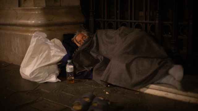 Un hombre sin hogar duerme en el Paseo de Gracia con Gran Vía de Les Corts Catalans