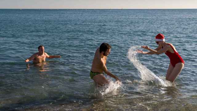 Unos jóvenes se bañan en la playa de la Barceloneta, a 25 de diciembre de 2022, en Barcelona