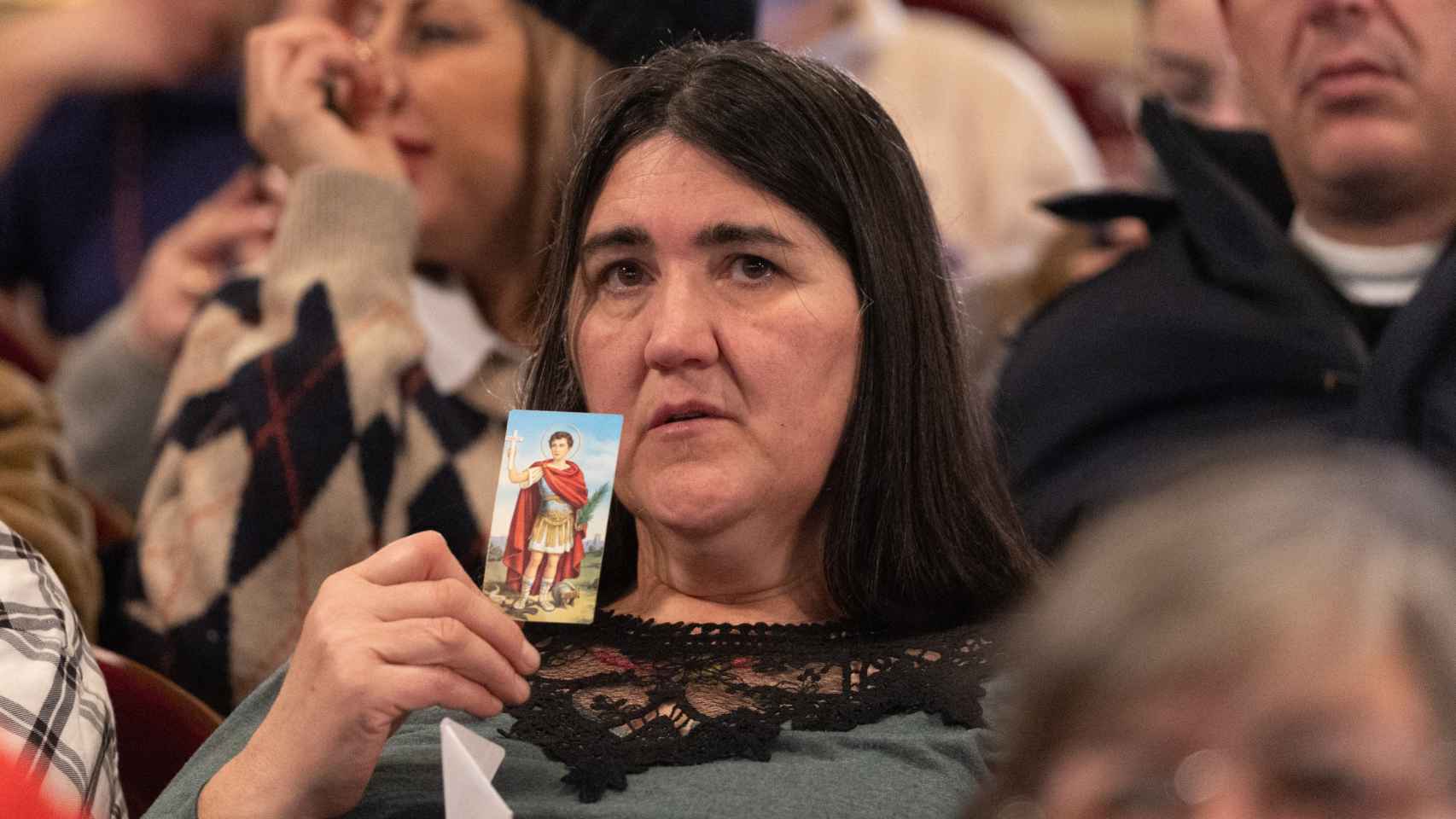 Una mujer sujeta la foto de una virgen durante la celebración del Sorteo Extraordinario de la Lotería de Navidad 2023