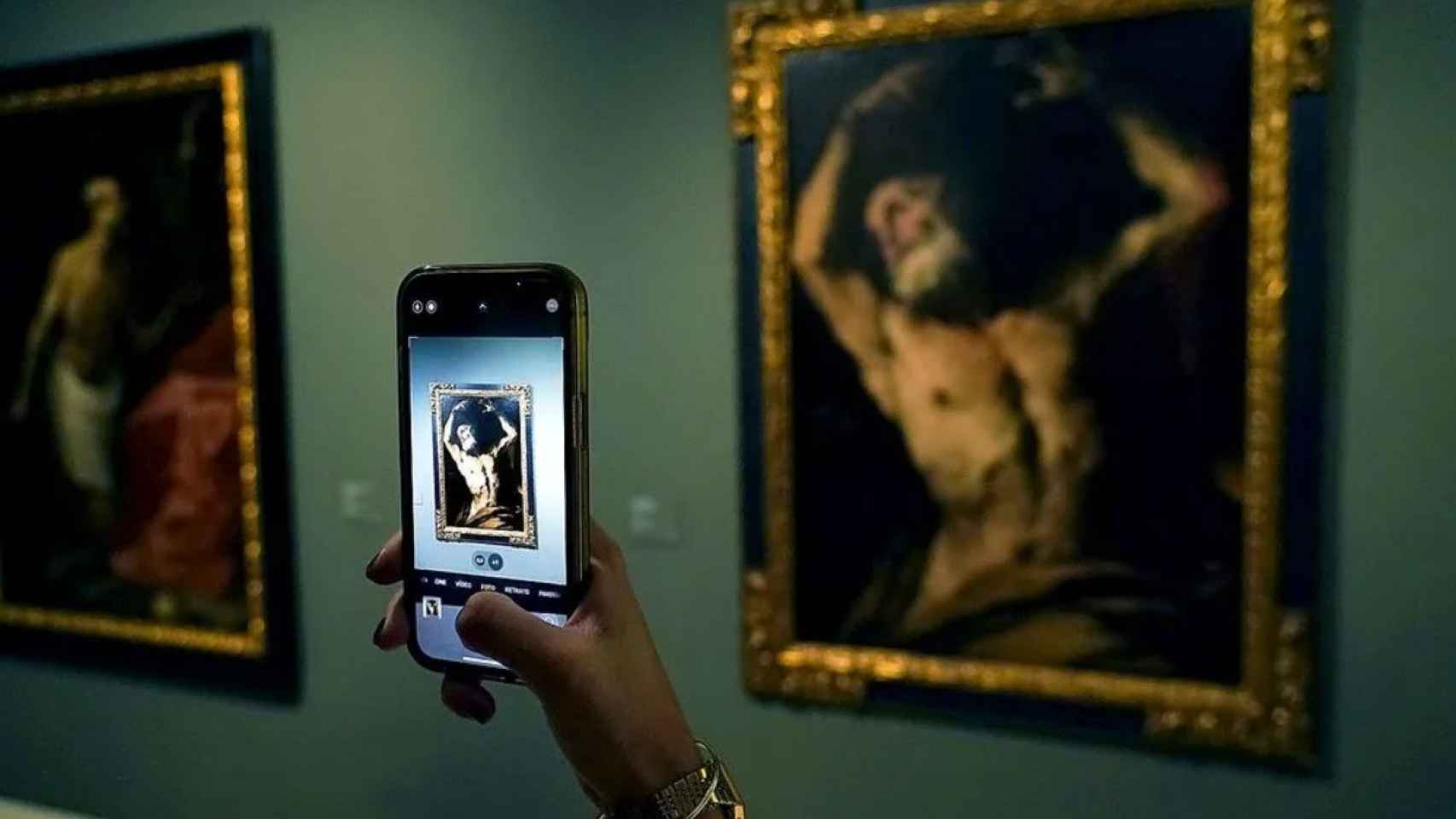 Un visitante toma fotografías con su móvil del lienzo de Luca Giordano ‘Martirio de san Bartolomé’.