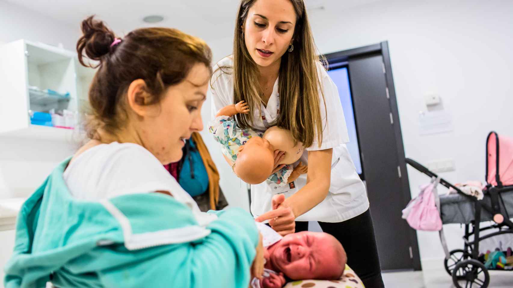 Una matrona ayuda a una madre en la posición para dar el pecho a su bebé en una sesión grupal sobre lactancia materna