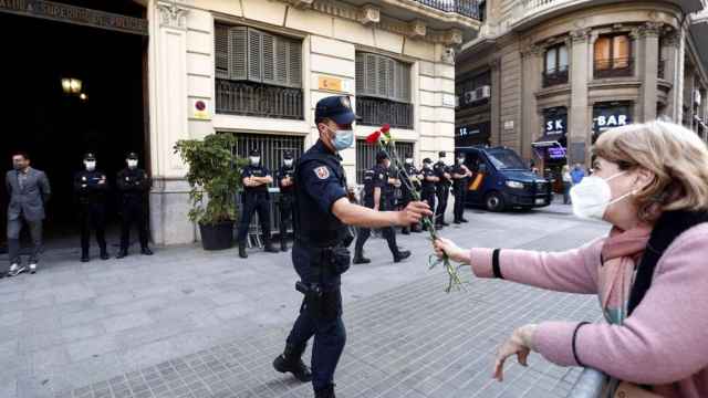 Una ciudadana entrega una flor a un agente ante la Jefatura Superior de Policía de Cataluña