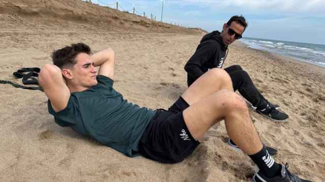 Gavi hace abdominales en la playa junto a un fisioterapeuta