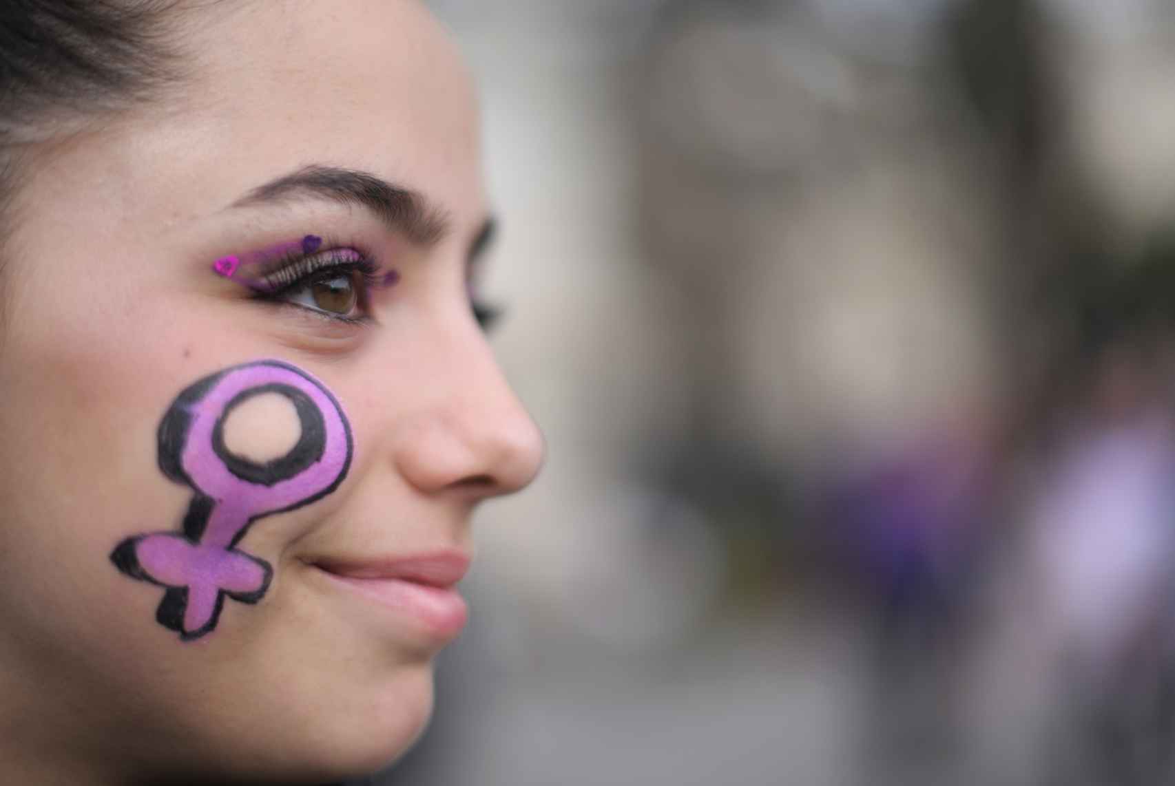 Mujer en una manifestación del 8M con el símbolo de Venus en la cara