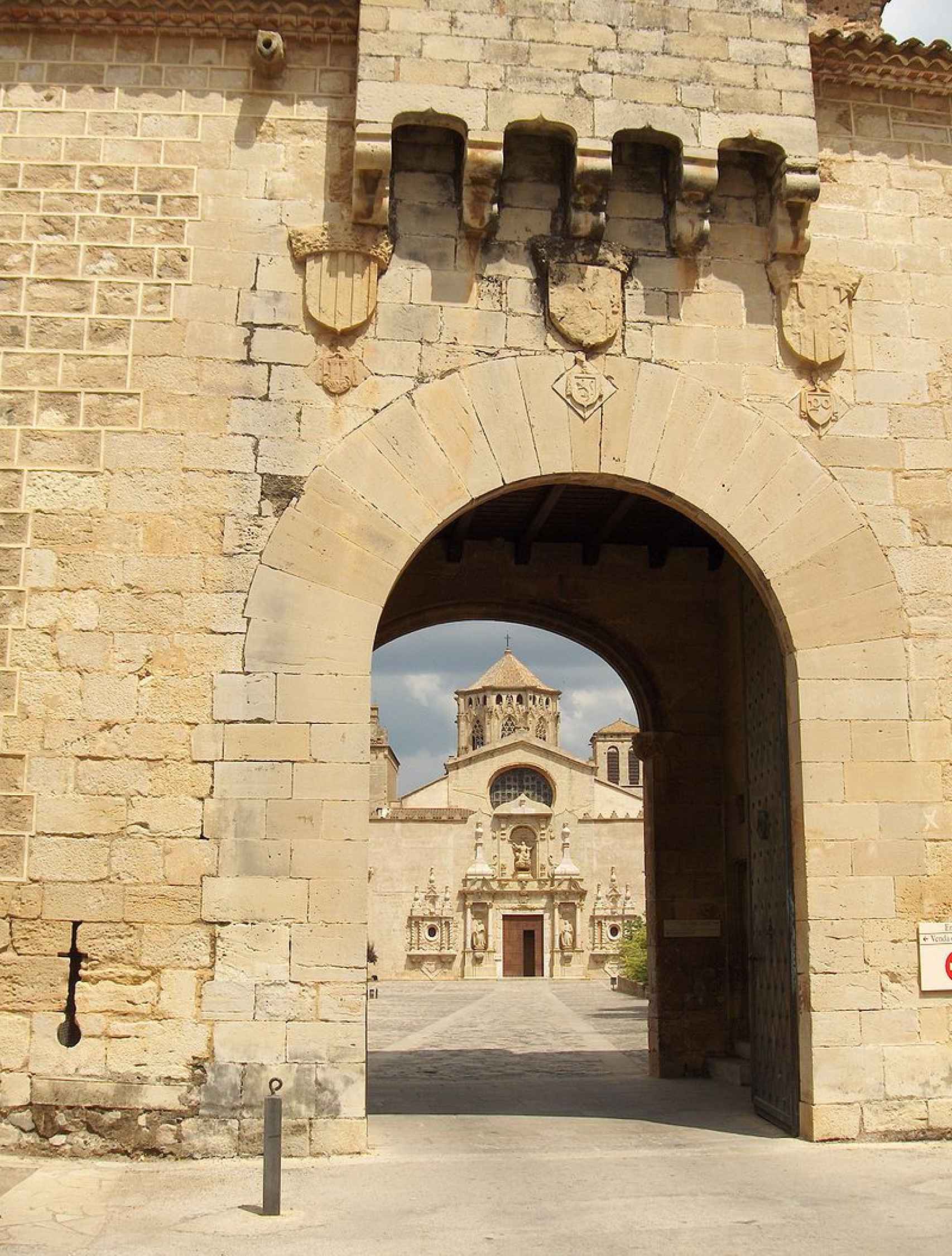 Puerta dorada de Poblet y al fondo la puerta barroca de la iglesia