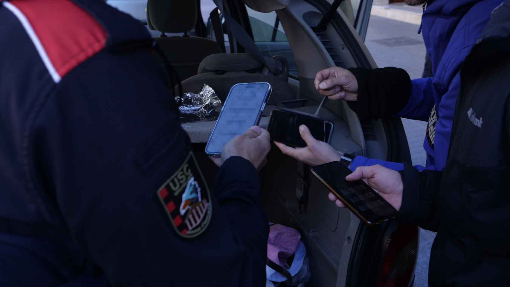 Agentes de los Mossos d'Esquadra revisando los teléfonos móviles localizados