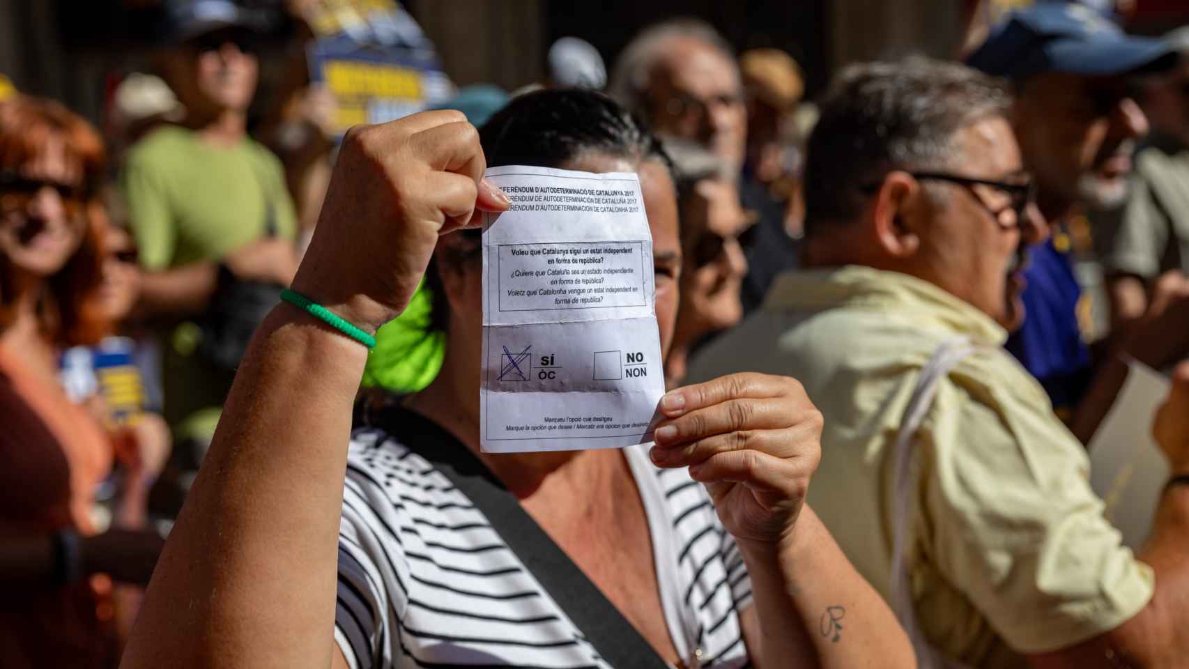Una manifestante muestra una papeleta de voto durante la celebración del aniversario del referéndum del 1-O, en 2023