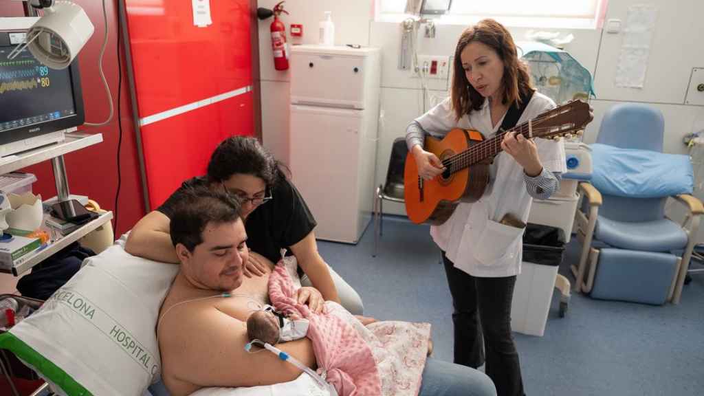 Un paciente de la UCI neonatal del Clínic recibe musicoterapia mientras está en contacto piel con piel con su padre