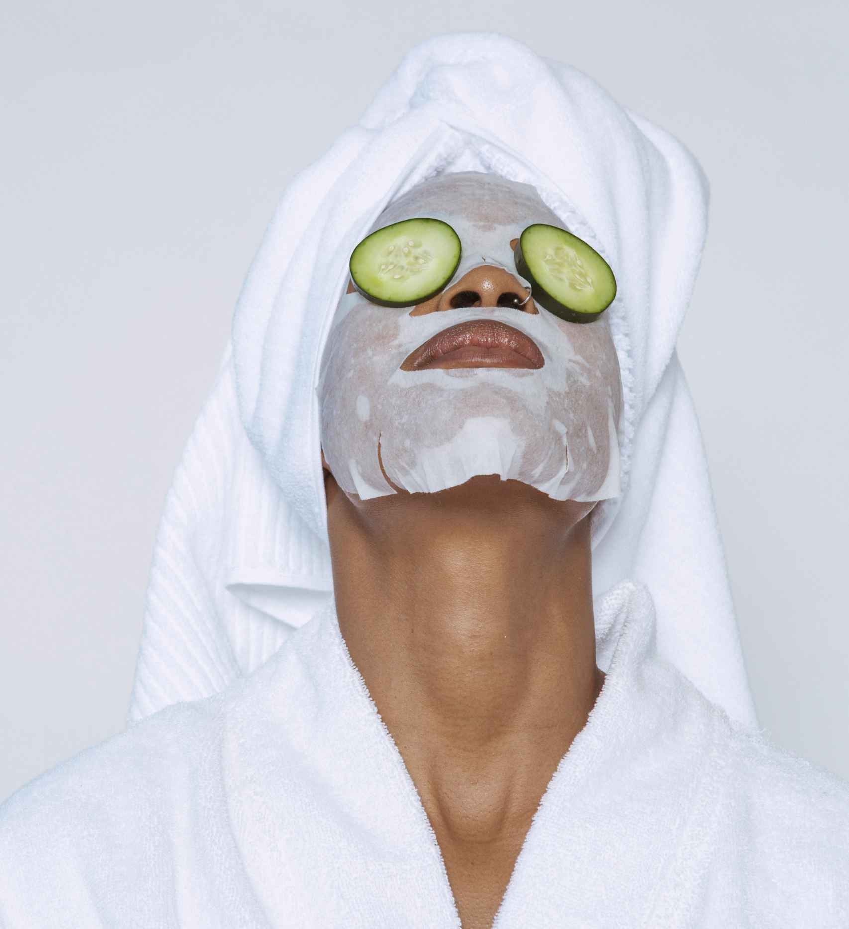 Chica con mascarilla facial y pepinos en los ojos