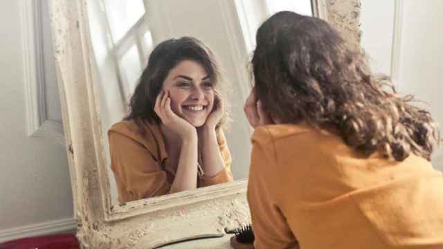 Imagen de archivo de una mujer sonriendo ante el espejo