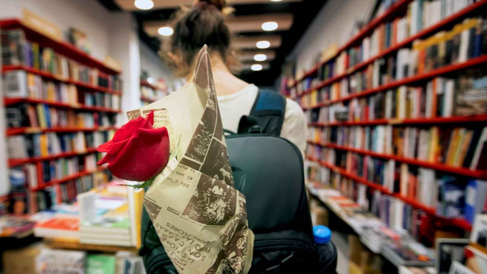 Una persona entra en una librería con una rosa en su mochila