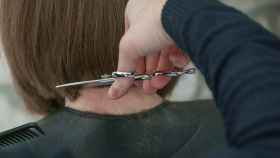 Un peluquero corta el pelo a una clienta, en una imagen de archivo