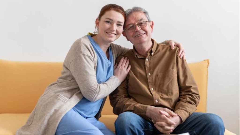 Cuidadora sonrie junto a un hombre mayor