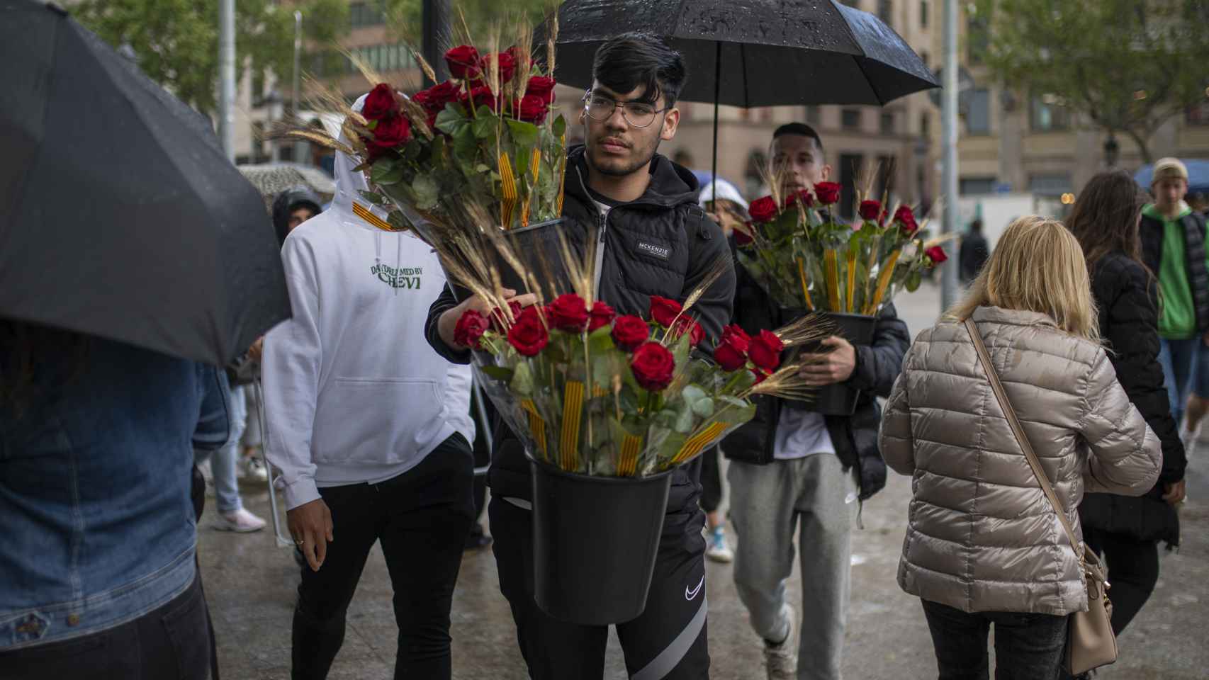 Dos hombres llevan rosas durante la feria literaria de Sant Jordi, en el día Internacional del Libro, en Las Ramblas, a 23 de abril de 2022