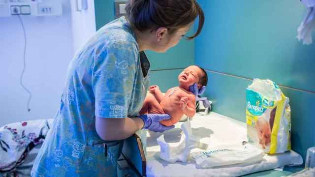 Una matrona sujeta un bebé recién nacido