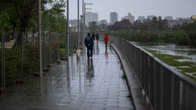 Varias personas pasean bajo la lluvia en Santa Coloma de Gramenet (Barcelona), a finales de abril