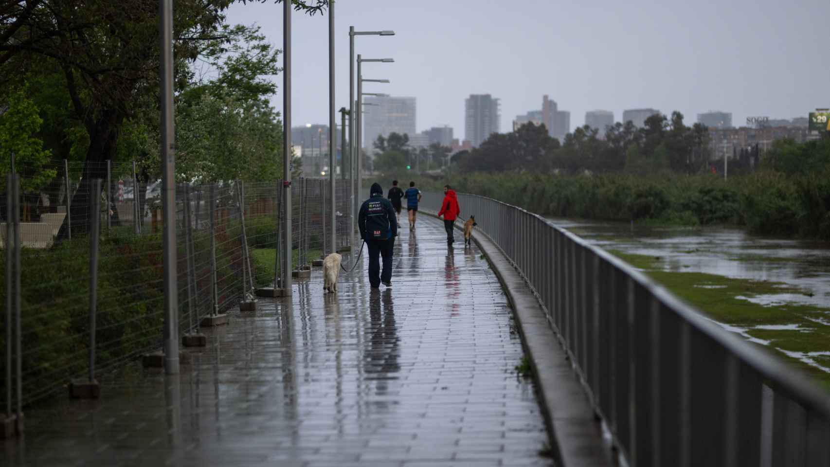 Varias personas pasean bajo la lluvia en Santa Coloma de Gramenet (Barcelona)