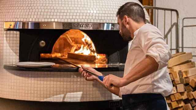 Un cocinero pone una pizza en un horno de leña