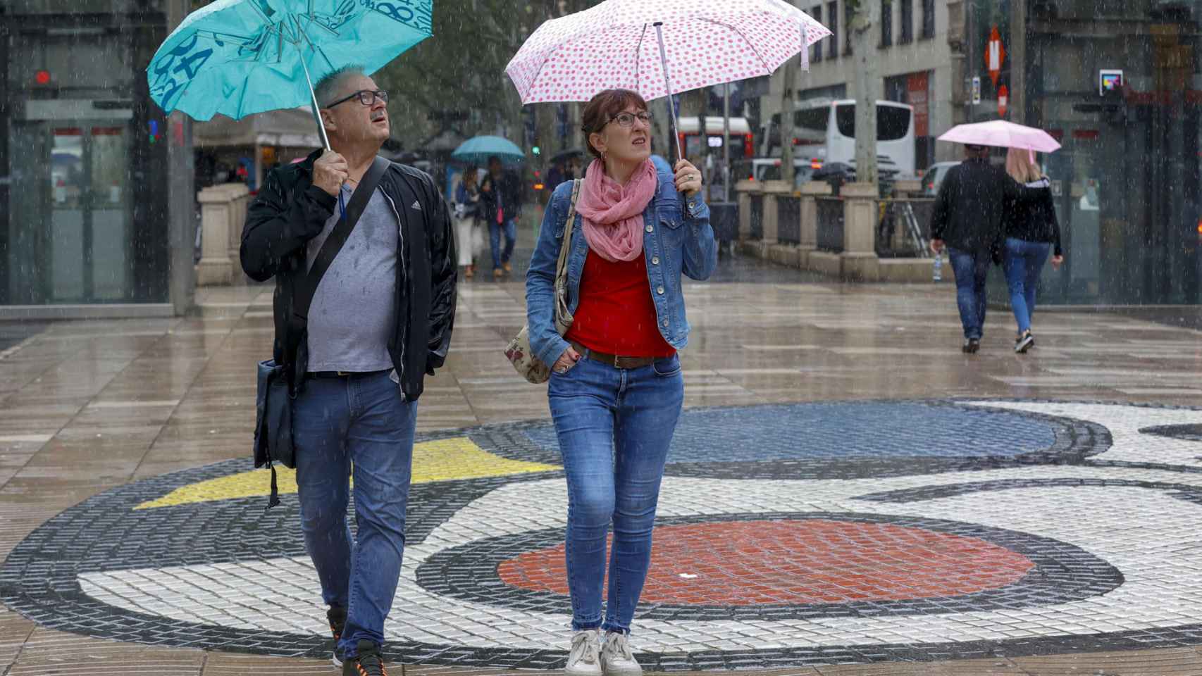 Varias personas se protegen de la lluvia mientras caminan por las Ramblas de Barcelona