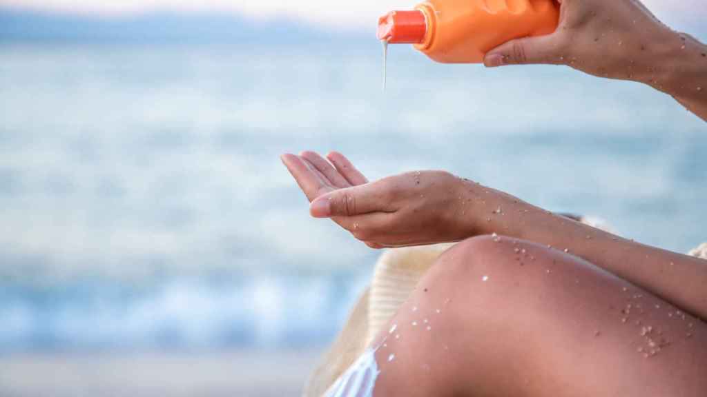 Una mujer se extiende crema solar para proteger la piel de los efectos del sol