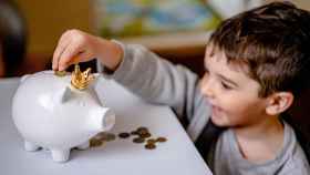 Un niño mete monedas en su hucha: es importante enseñar a los más pequeños a gestionar su dinero
