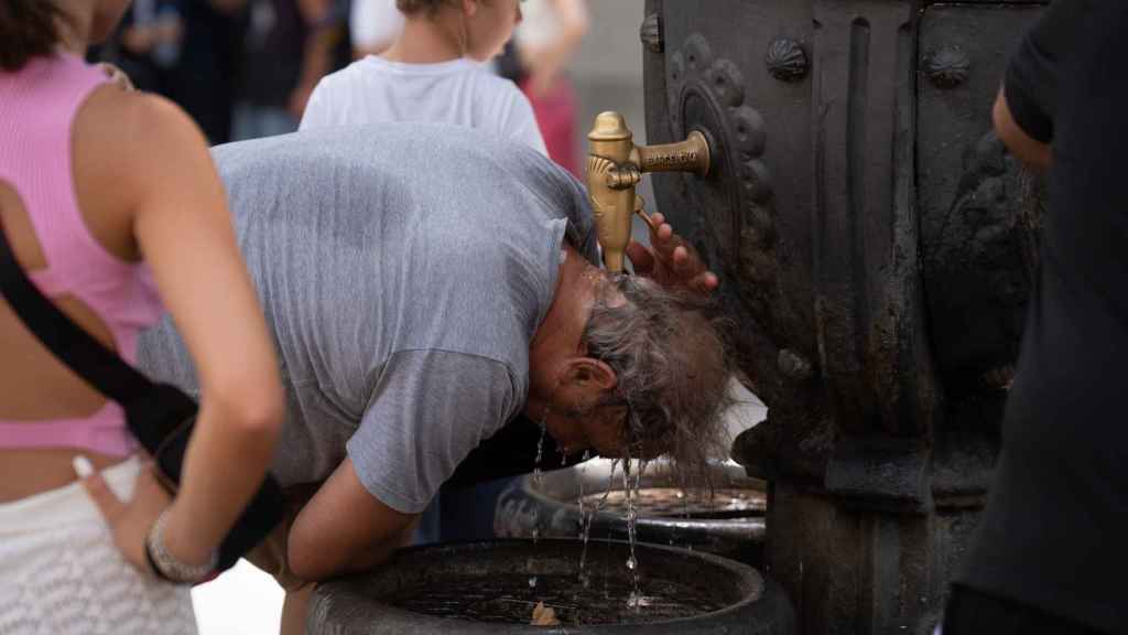 Una persona se refresca en la fuente de Canaletes