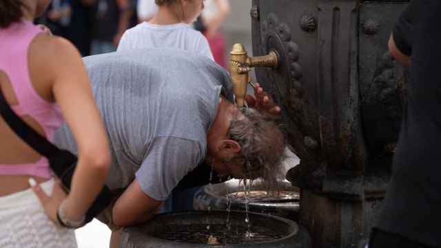 Una persona se refresca en la fuente de Canaletes