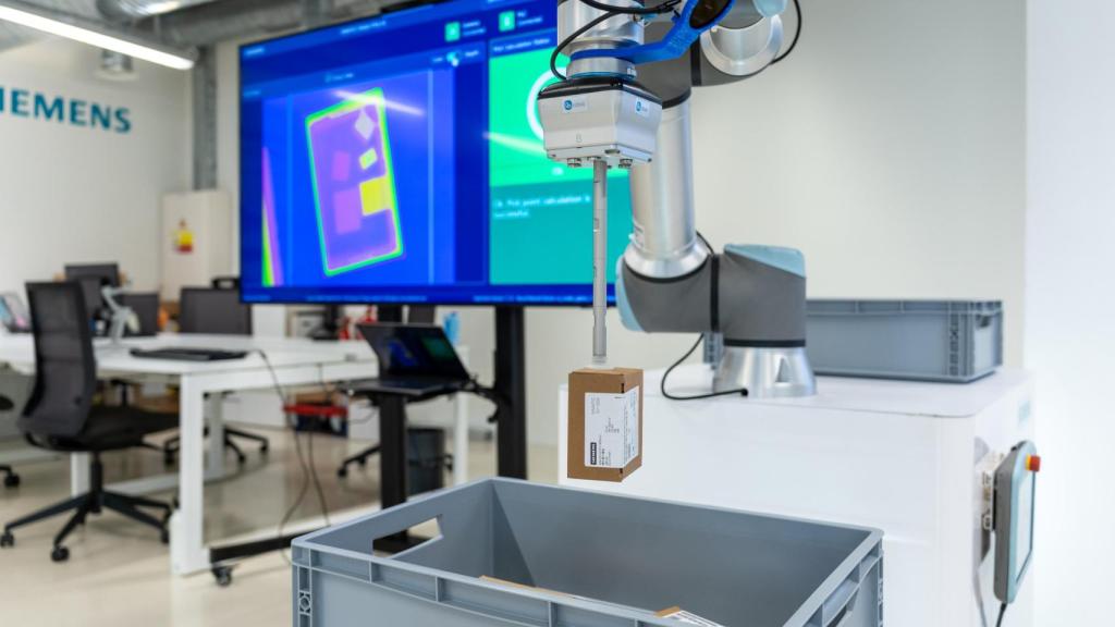 Con tecnologías como SIMATIC PICK AI, Siemens ha desarrollado un sistema que permite a un brazo robótico recoger piezas no registradas previamente, utilizando visión artificial