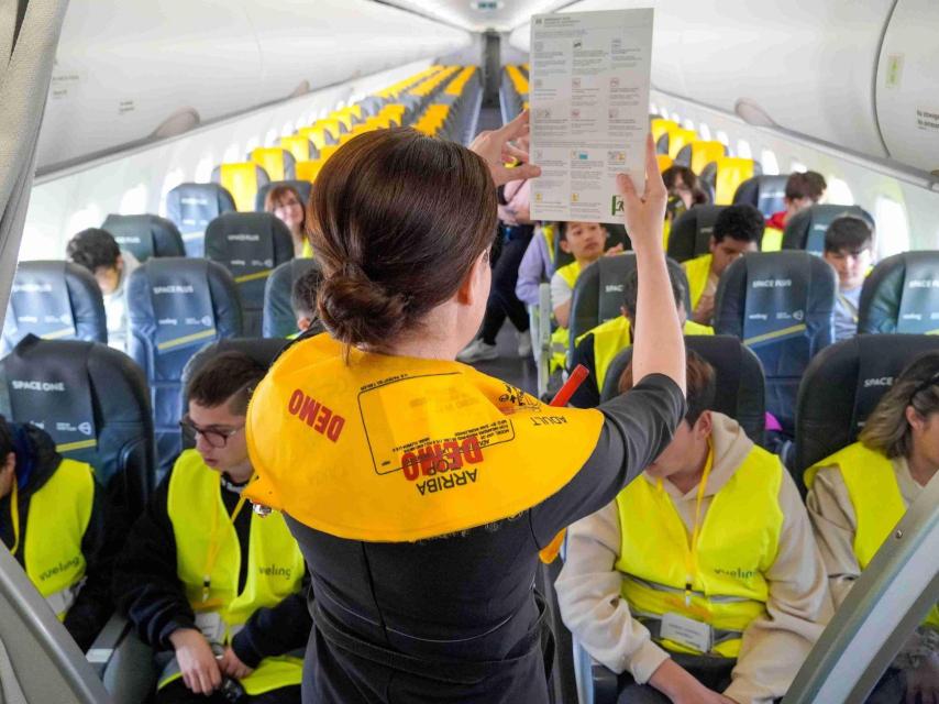 Una auxiliar de vuelo instruye en medidas de seguridad a unos niños