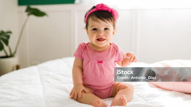 Una bebé con un vestido y una diadema rosa