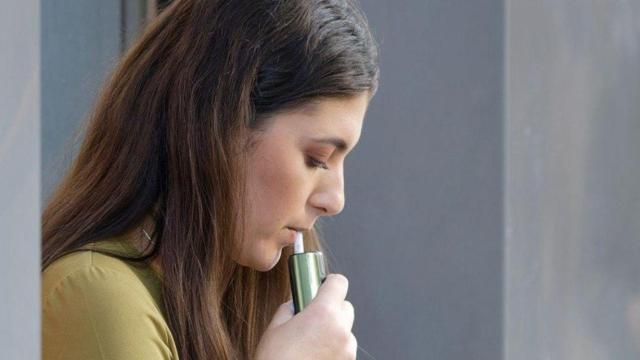 Una chica usando un dispositivo de tabaco calentado