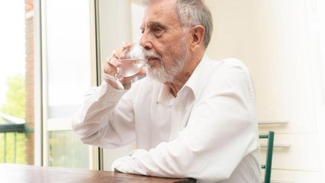 Un hombre mayor toma agua fresca en verano
