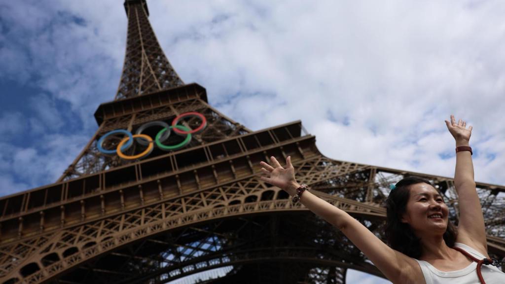 Una turista se fotografía en la Torre Eiffel con los aros olímpicos