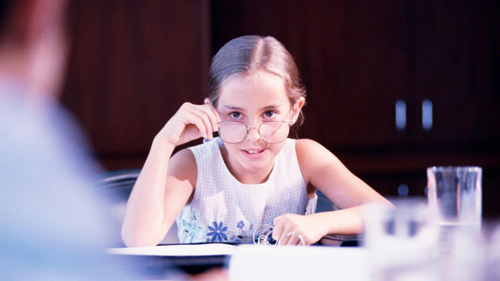 Una niña mira por encima de sus gafas