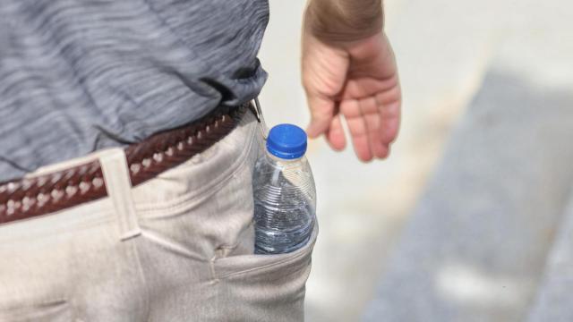 Una persona pasea con una botella de agua en el bolsillo