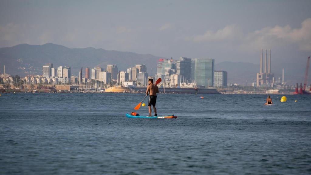 Un hombre practica paddle surf en una playa en Barcelona