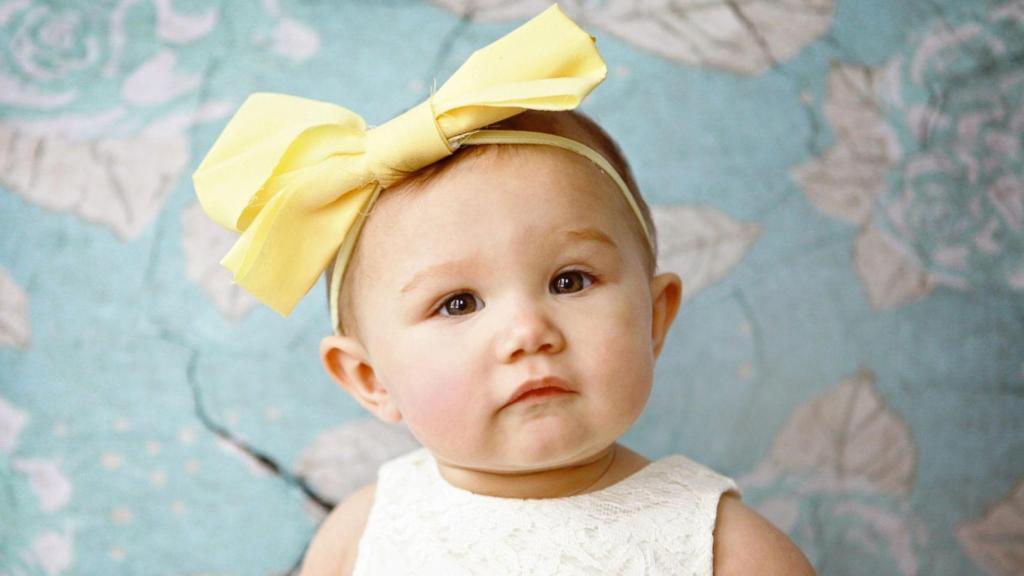 Una bebé con un lazo amarillo en la cabeza