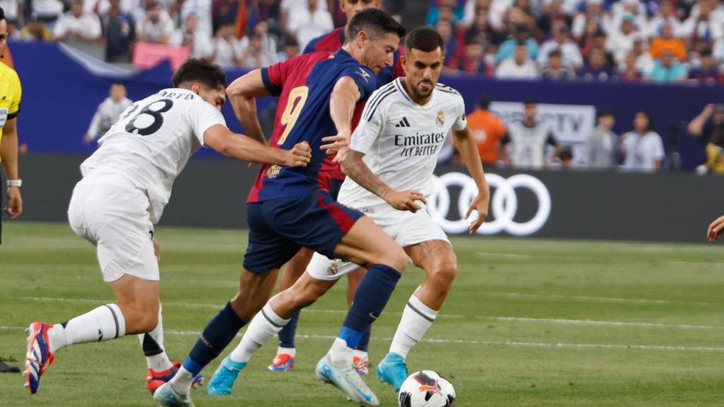 Lewandowski controla el balón ante dos jugadores del Real Madrid.