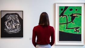 Una mujer observa dos obras de Miró en el CAHH