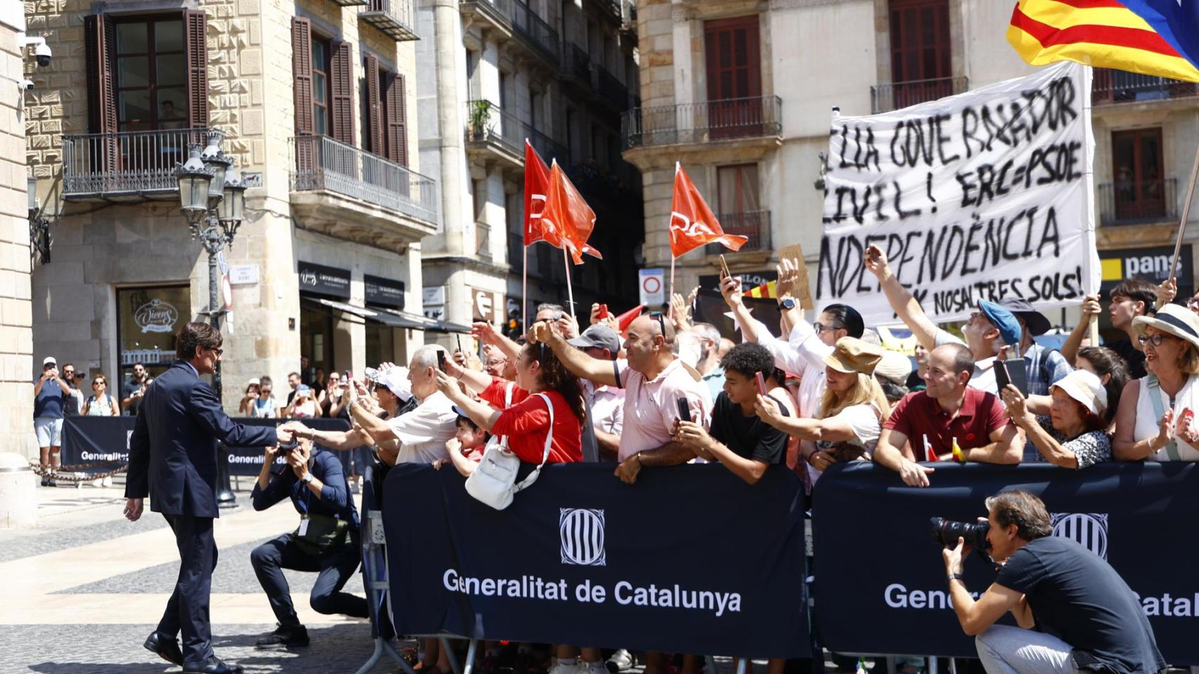 Salvador Illa, nuevo presidente de la Generalitat, se acerca a decenas de seguidores, con un grupo de detractores independentistas detrás