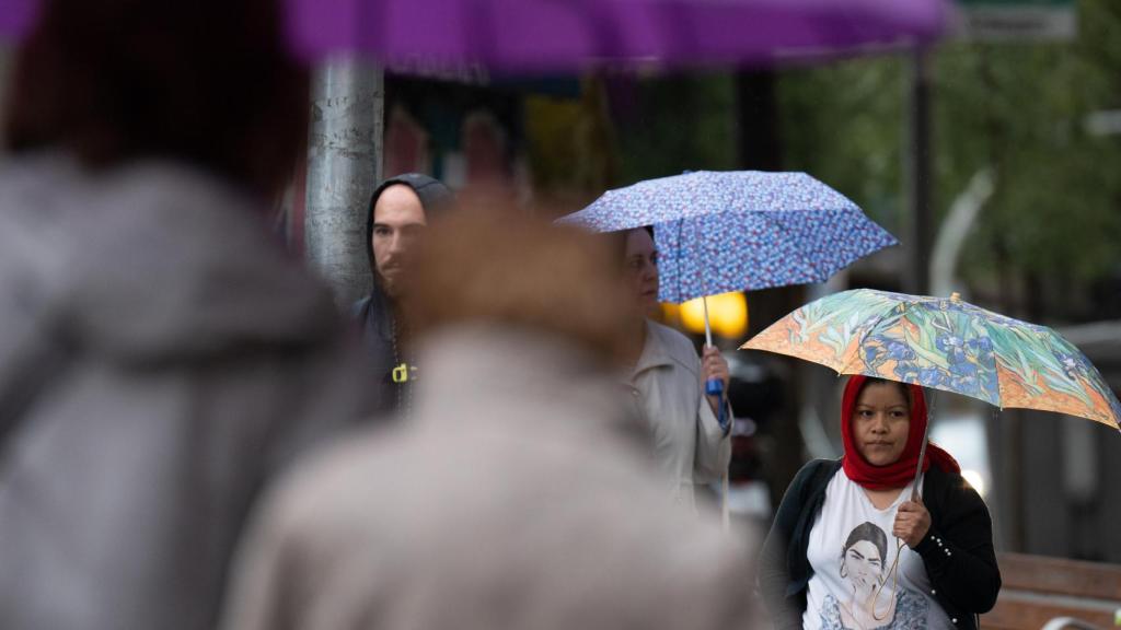 Varias personas con paraguas pasean por una de las calles de Barcelona