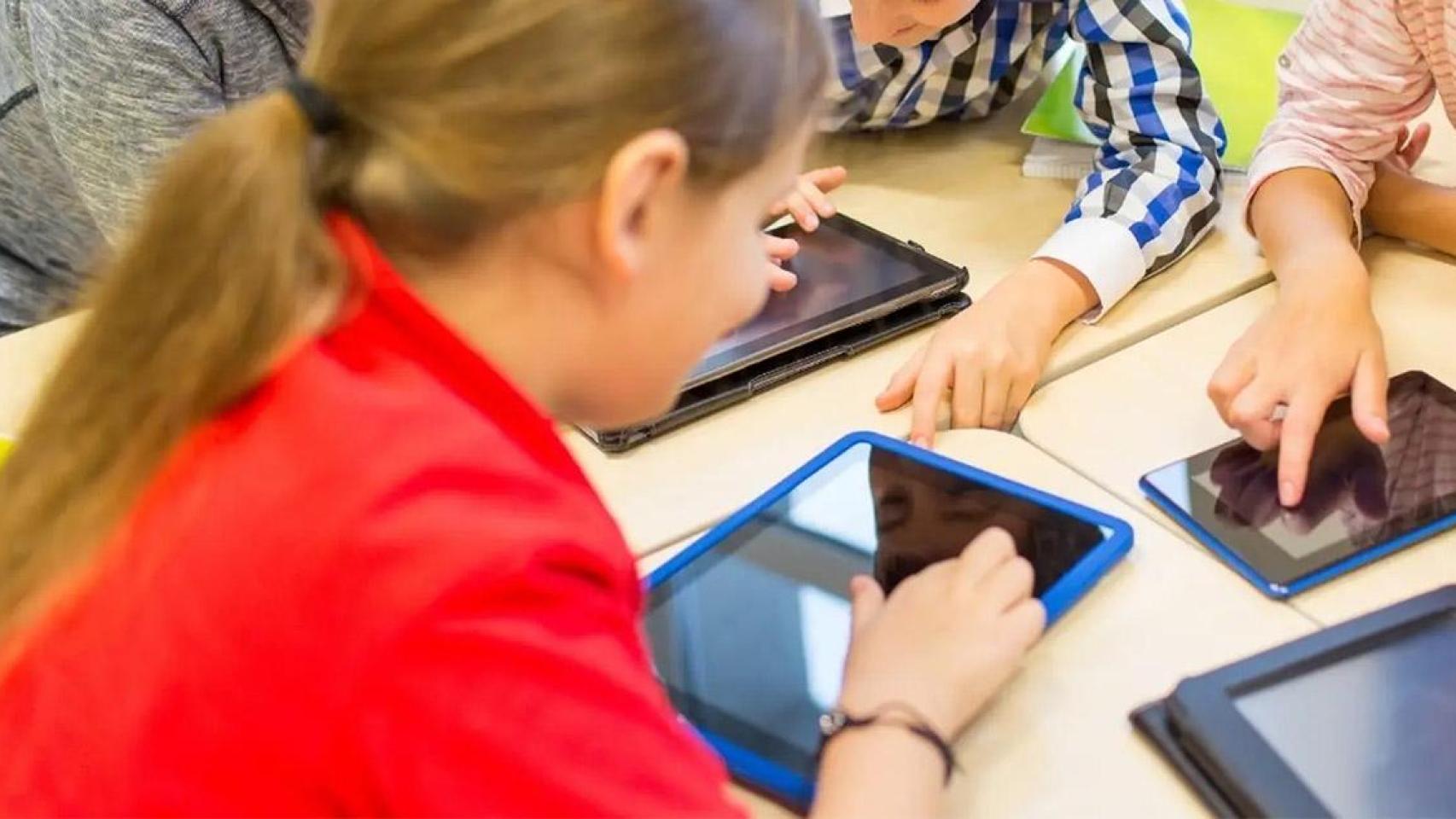 Imagen de archivo de varios niños usando tablets en un centro escolar