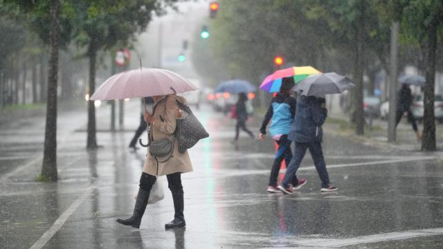 Varias personas caminando bajo la lluvia