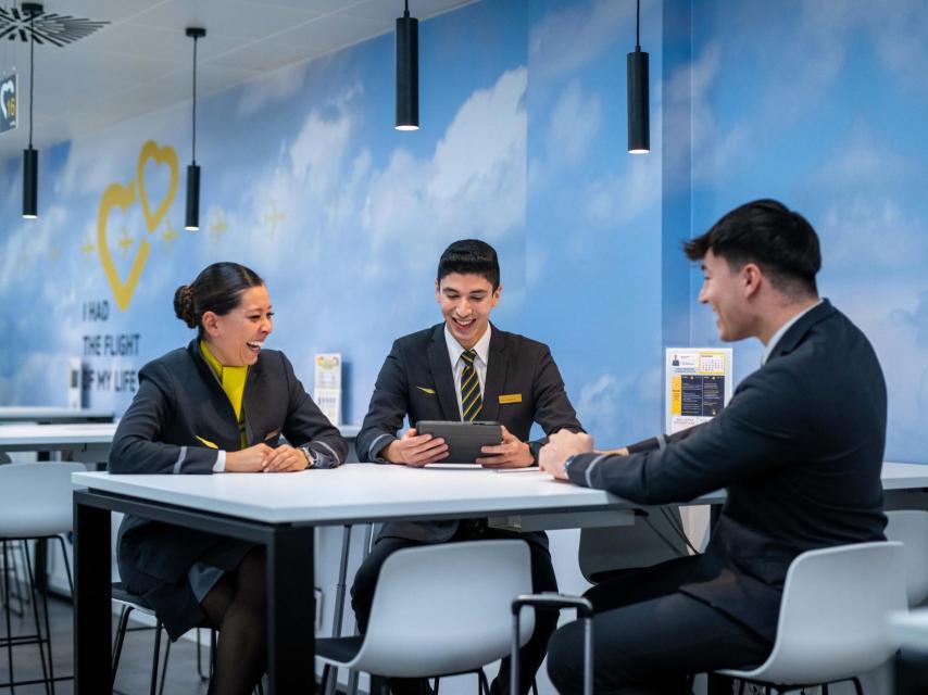 Tres jóvenes miembros de la tripulación de Vueling conversan animadamente