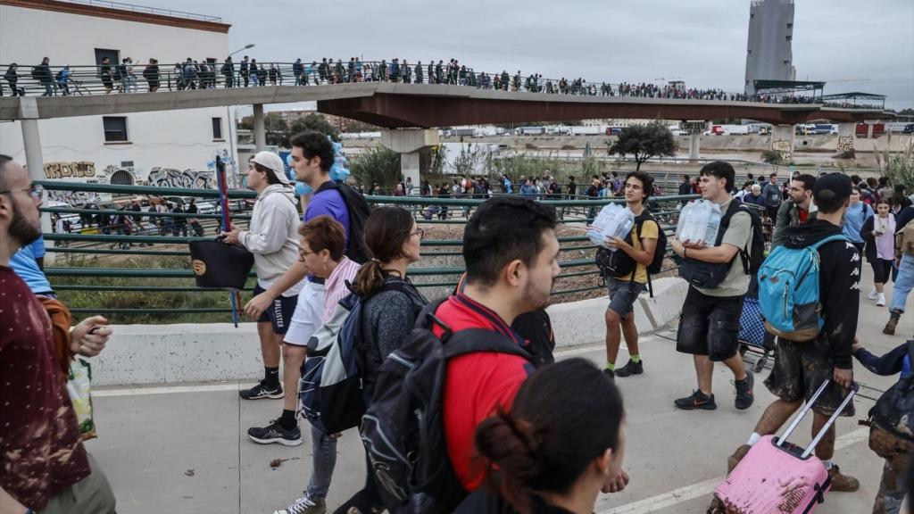 Decenas de personas en el puente que une València con La Torre, donde centenares de personas llegan de Valencia de abastecerse de agua y alimentos mientras otras salen de ayudar