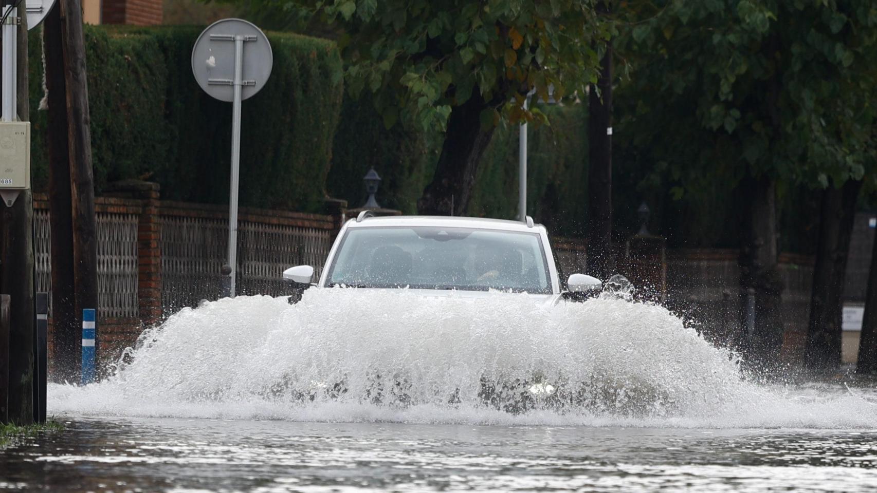 Un coche circula por una calle inundada