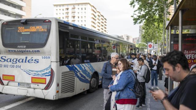 Varios pasajeros esperan para subir a un autobús público