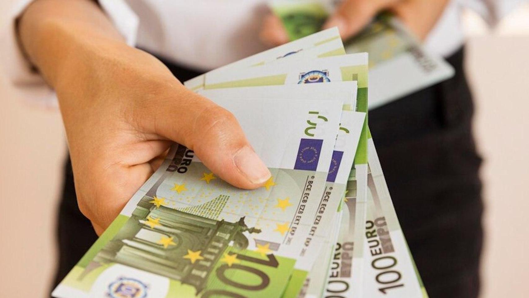 Un hombre entrega unos billetes de cien euros